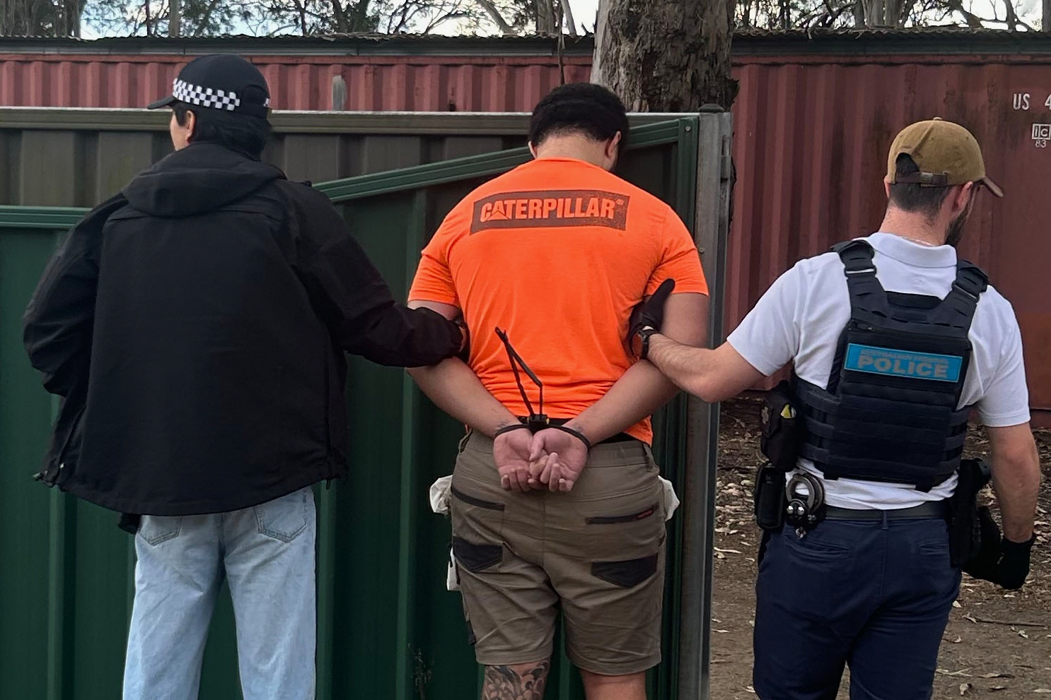 In this photo provided by the Australian Federal Police, a man, center, is arrested by police in Londonderry in western Sydney, Friday, June 19, 2026.